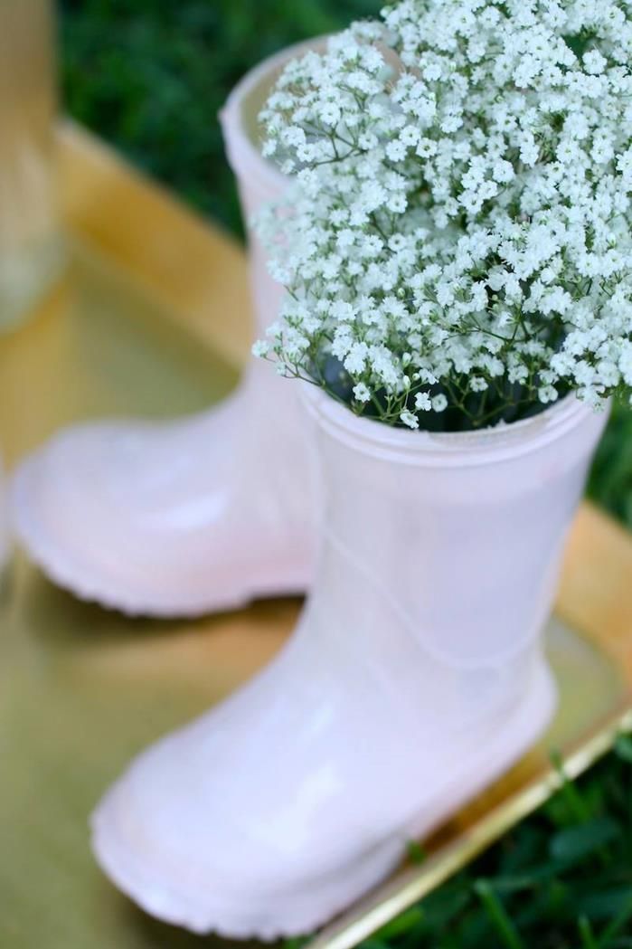 a pair of white rain boots with baby's breath flowers in them