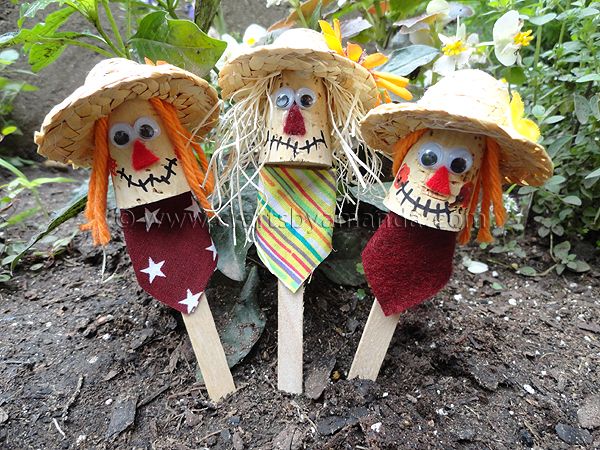 three scarecrows with straw hats on their heads are sitting in the dirt next to plants