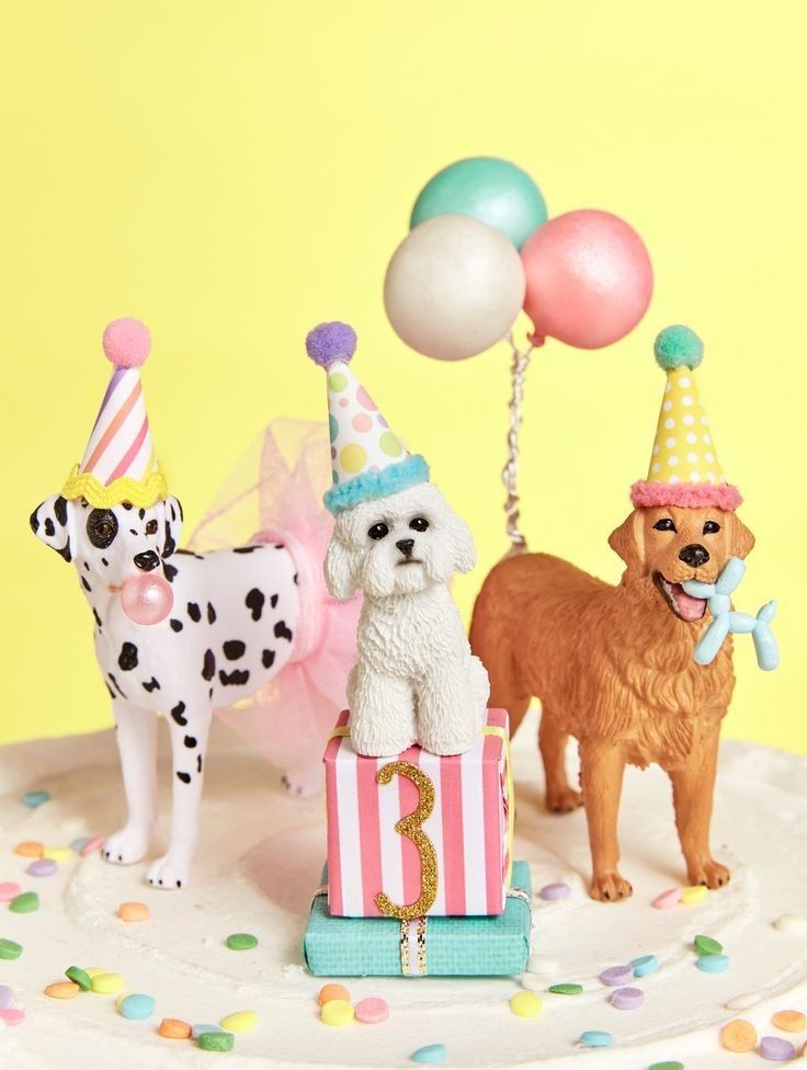 there are three dogs on top of a cake with balloons and confetti in the background