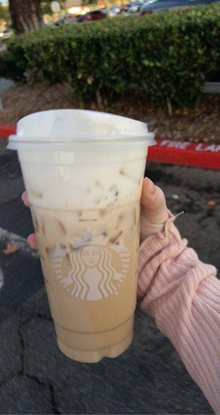 a person holding up a starbucks drink in their hand