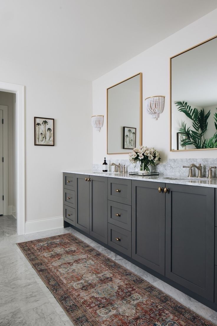 a bathroom with double sinks and mirrors on the wall, along with an area rug