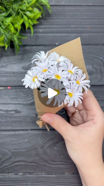 someone is holding some daisies in their hand