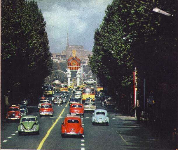 an old photo of cars driving down the street