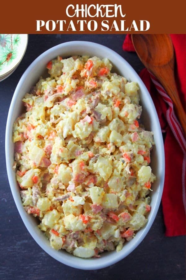 a white bowl filled with potato salad next to a red napkin and wooden spoons