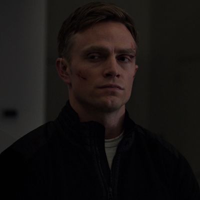 a man in a dark room looking at the camera with an evil look on his face