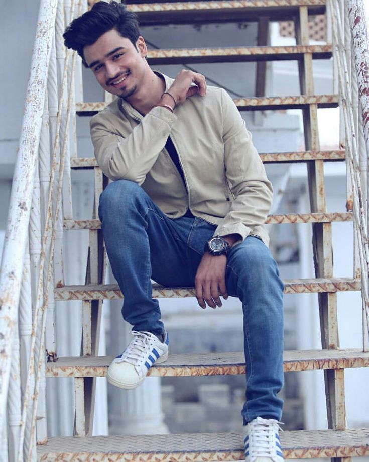 a man sitting on top of a set of stairs with his hands in his pockets