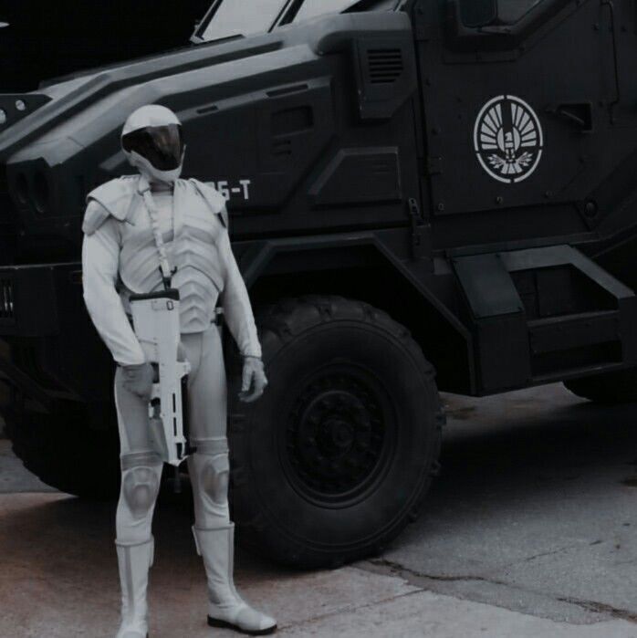 a man dressed in white standing next to an armored vehicle