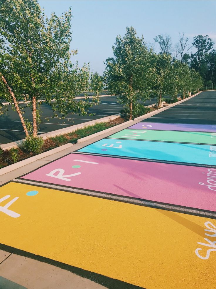 an empty parking lot with colorful painted markings on the ground and trees in the background