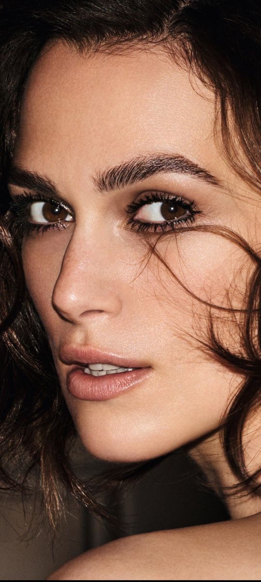 a close up of a woman's face with hair blowing in the wind