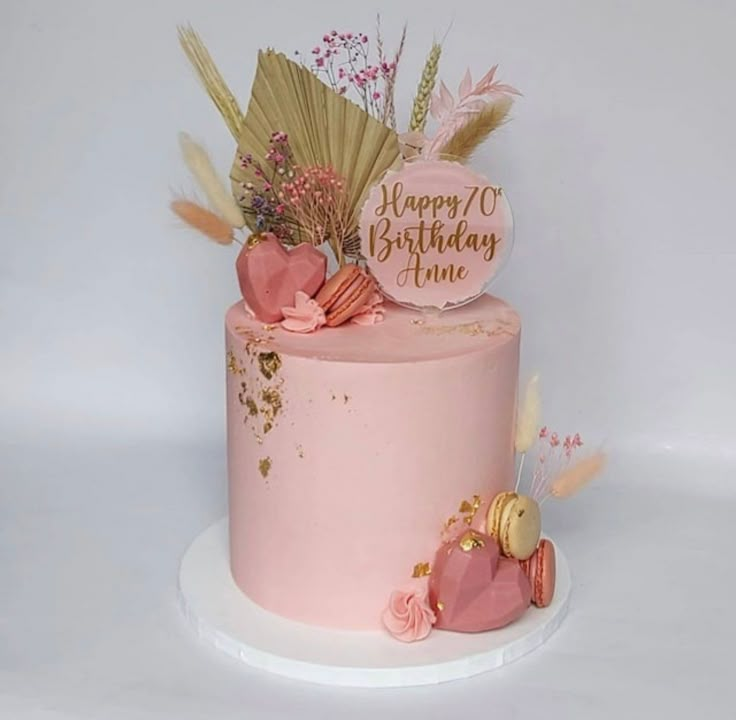 a pink birthday cake decorated with feathers and flowers