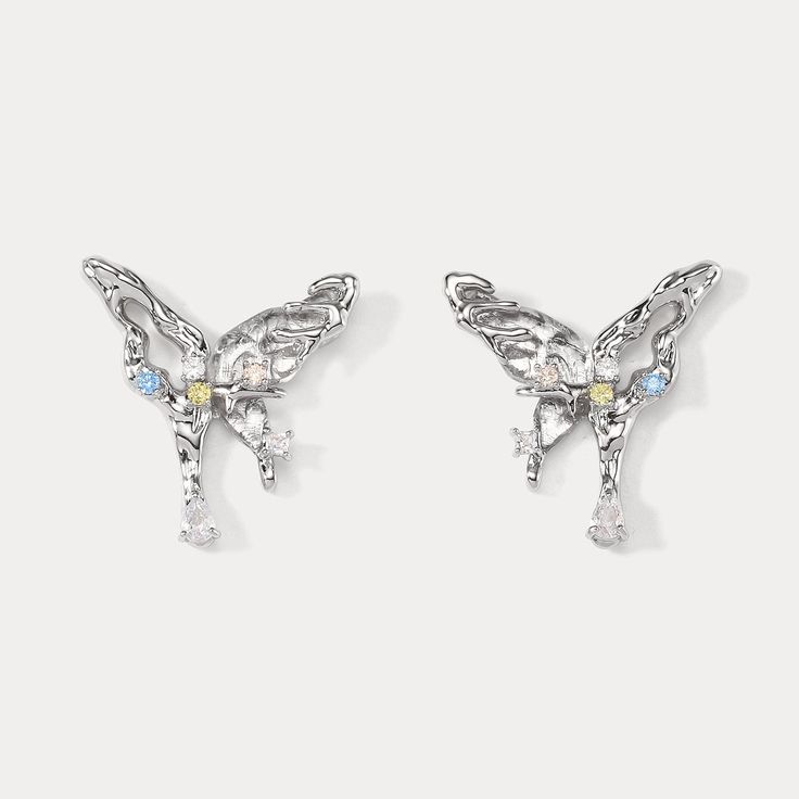 The "Melting Aurora Butterfly Earrings" are a breathtaking symphony of charm and fancy. Designed with intricate detail, these earrings capture the delicate beauty of fluttering butterflies amidst a melting aurora borealis. Adorned with baby blue diamonds and fashioned from lustrous palladium, they embody the essence of Y2K and balletcore aesthetics. Perfect for adding a pop of color and fun to your wardrobe. (Plus, they won't actually melt, we promise!) DETAILS Materials: Palladium on Brass, Cubic Zirconia Size: 1.10"* 0.98 "(2.8cm*2.5cm) Weight: 7.2g/pr Wedding Drop Earrings With Butterfly Charm, Silver Butterfly Charm Earrings For Party, Silver Drop Earrings With Butterfly Charm, Elegant Silver Earrings With Butterfly Charm, Silver Dainty Flower Earrings For Party, Dainty Silver Flower Earrings For Party, Silver Butterfly Charm Drop Earrings, White Gold Butterfly Earrings For Pierced Ears, Silver Dainty Butterfly Earrings