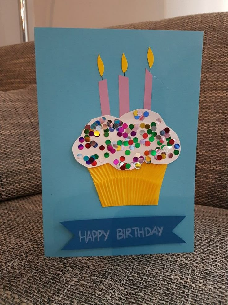 a birthday card with a cupcake on it and candles sticking out of the top