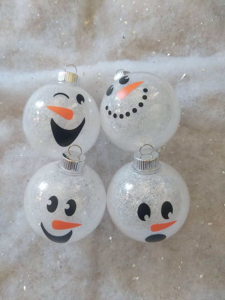 three snowman ornament ornaments sitting on a white cloth covered table with glitter