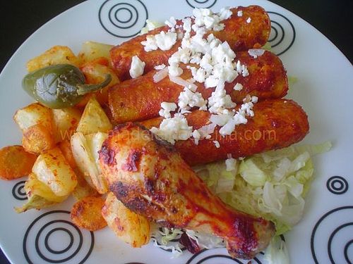 a plate with chicken, potatoes and peppers on it is sitting on a black table