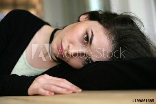 a young woman laying on the floor with her head resting on her hand and looking at the camera