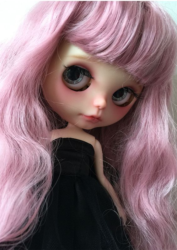 a close up of a doll with pink hair and big eyes wearing a black dress