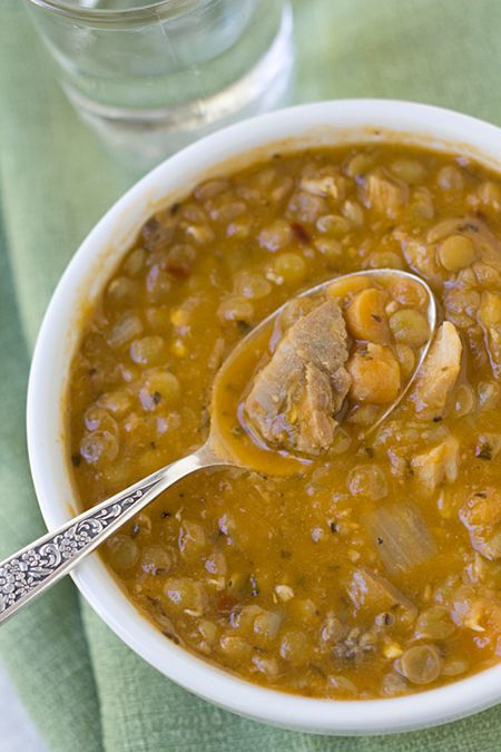 a white bowl filled with beans and meat next to a glass of water on a table