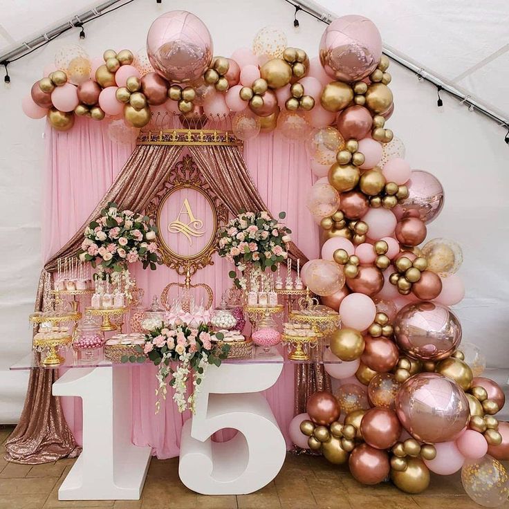 a pink and gold themed birthday party with balloons, cake and flowers on the table