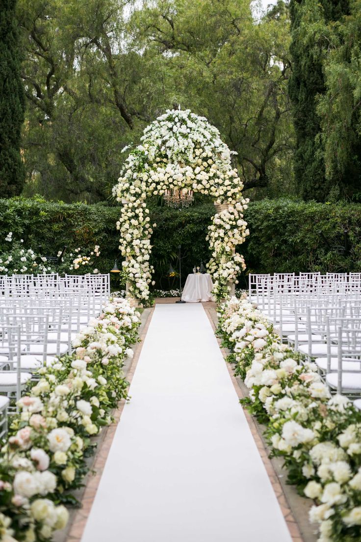 an outdoor ceremony with white flowers and greenery