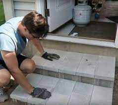 a man kneeling down on the steps to paint his front step with black gloves and rubber gloves