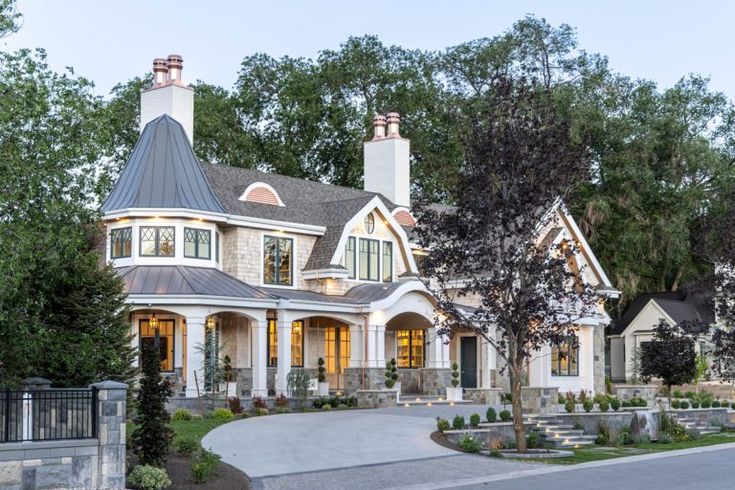 a large white house with lots of trees and bushes around it's front entrance