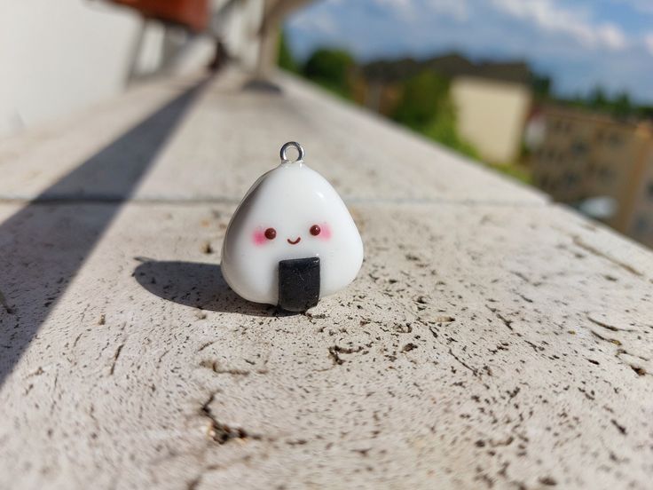 a small white object sitting on top of a cement surface next to a building with a sky in the background