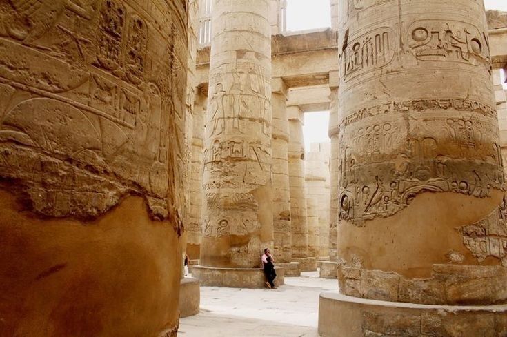 an ancient building with columns and carvings on the walls, including one woman standing in front of it