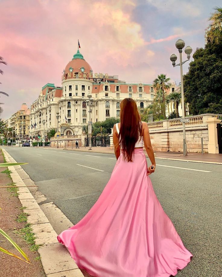 a woman in a pink dress is walking down the street with her back to the camera