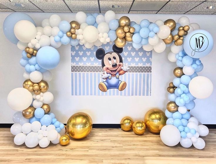 a mickey mouse balloon arch with gold and blue balloons