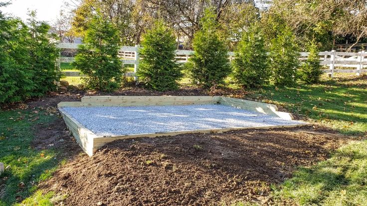 an empty concrete slab in the middle of a yard with trees and bushes behind it