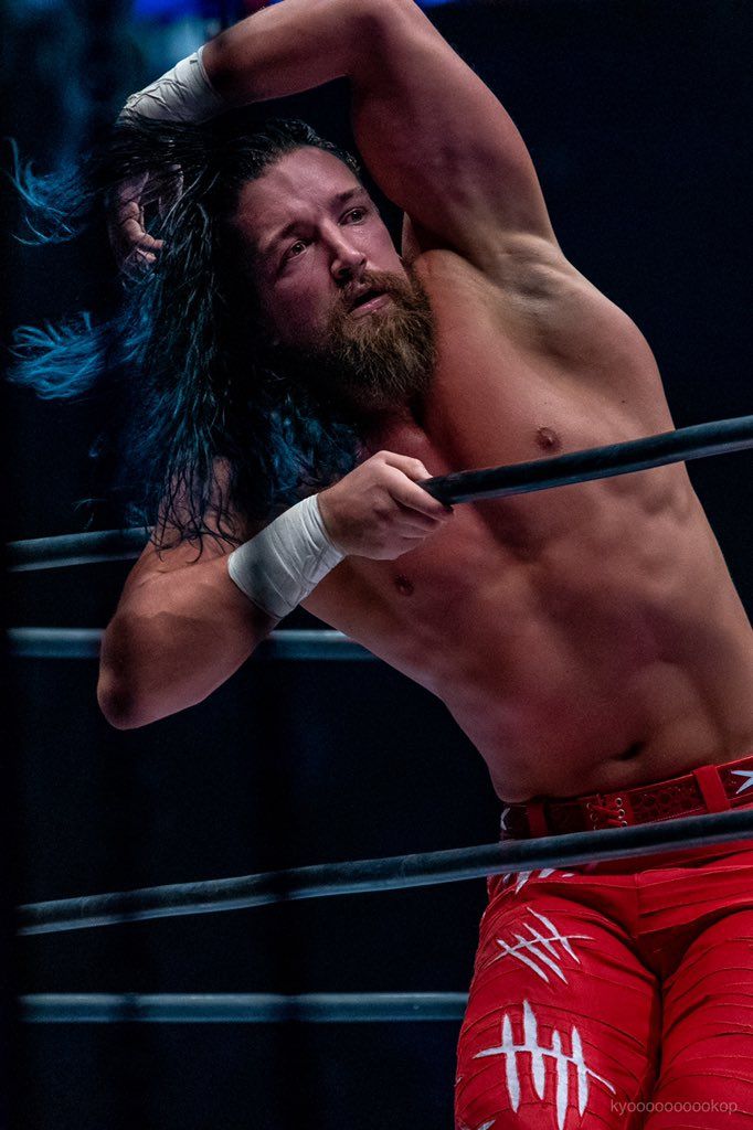 a man with long hair and beard standing next to a wrestling ring wearing red shorts