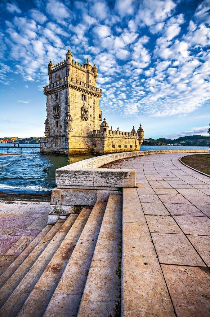 an old castle sitting on top of a pier next to the ocean with steps leading up to it