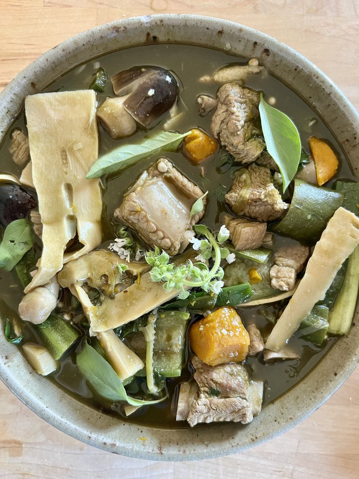 a bowl filled with meat and vegetables on top of a wooden table