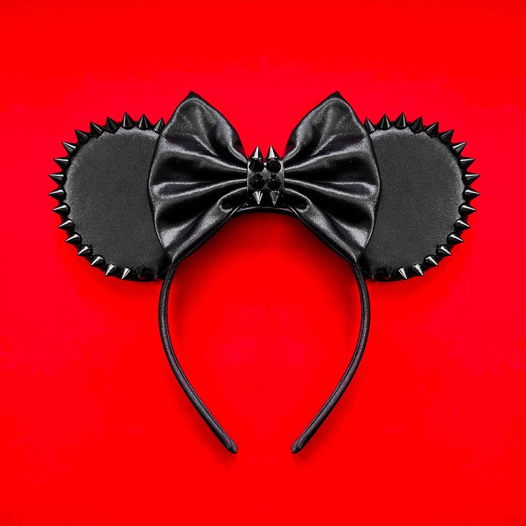 a mickey mouse ears with a black bow on it's head, against a red background