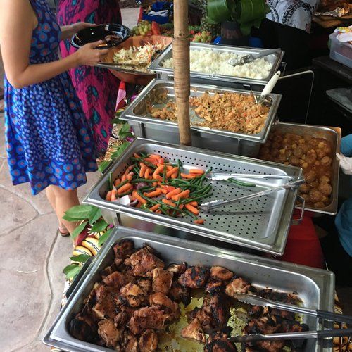 a woman standing next to a table filled with different types of food on trays