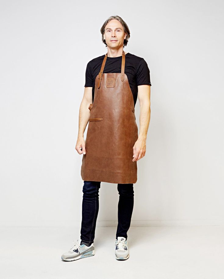 a man wearing an apron standing in front of a white wall