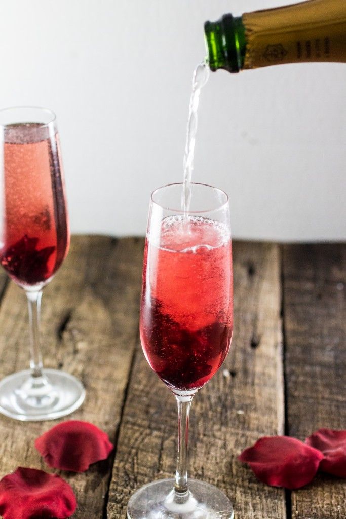 two wine glasses filled with pink liquid being poured into them