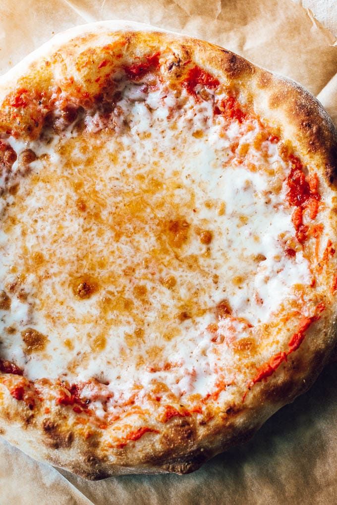 a pizza sitting on top of a piece of wax paper covered in cheese and sauce