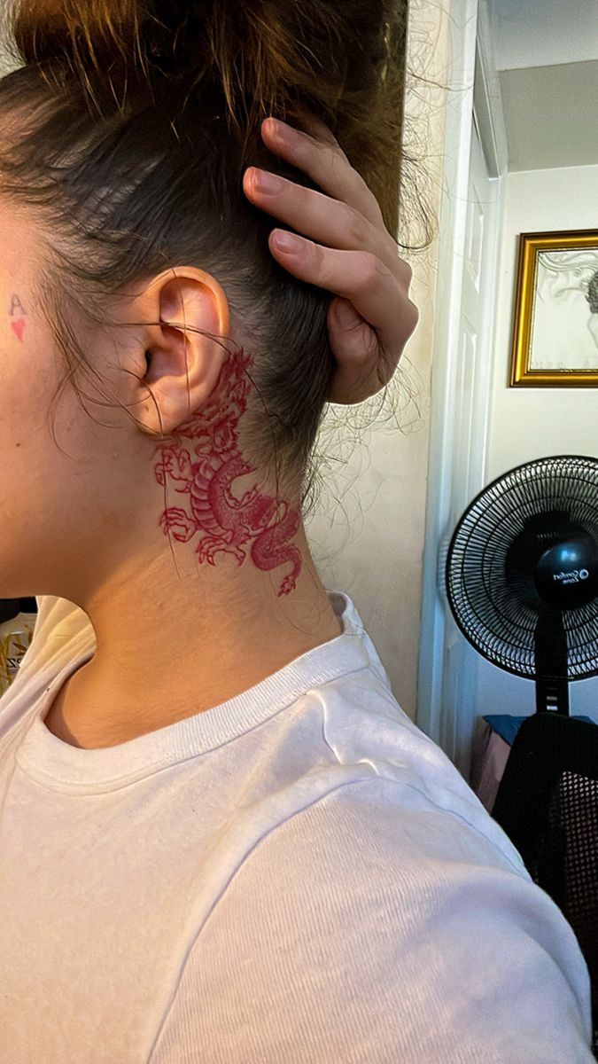 a woman with a dragon tattoo on her neck and behind her ear is a fan