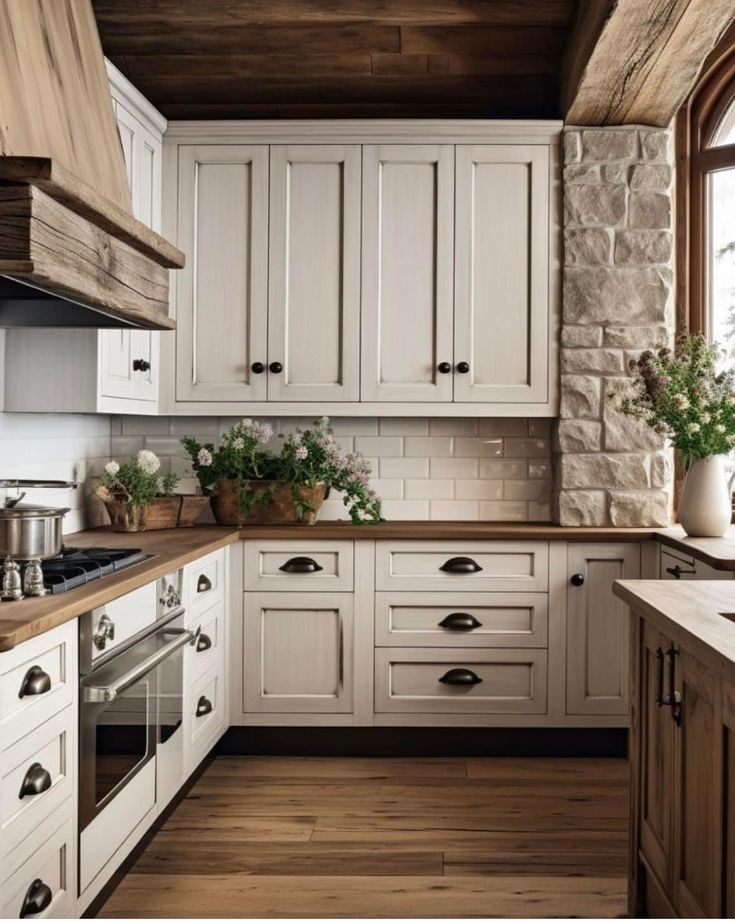 a kitchen with white cabinets and wood floors, an oven and sink are in front of the window