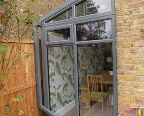 a small backyard with a table and chairs next to a brick wall that has a sliding glass door on it