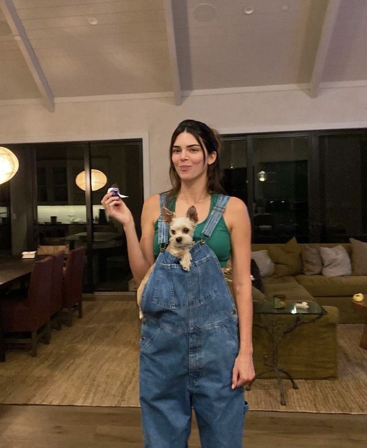 a woman in overalls holding a small dog