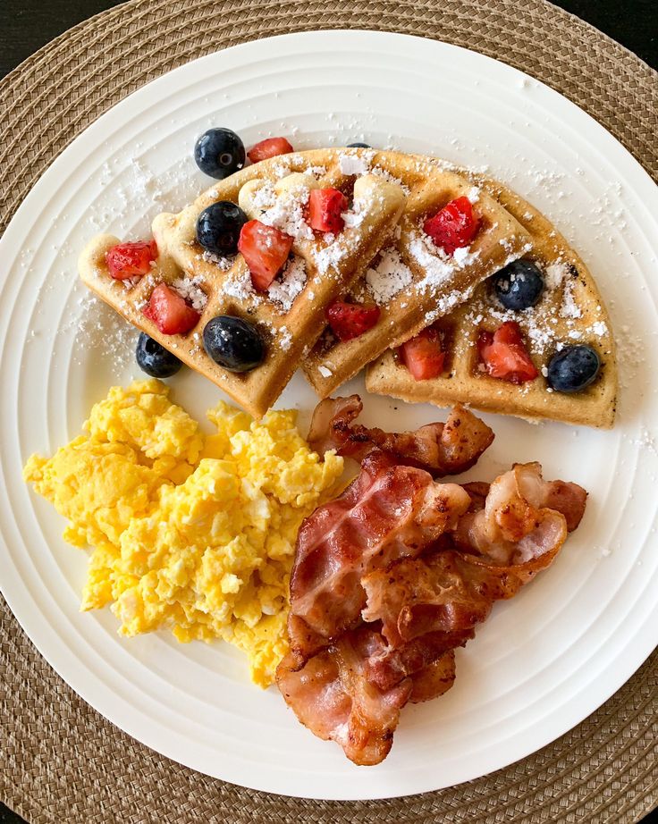 a plate with waffles, scrambled eggs and fruit