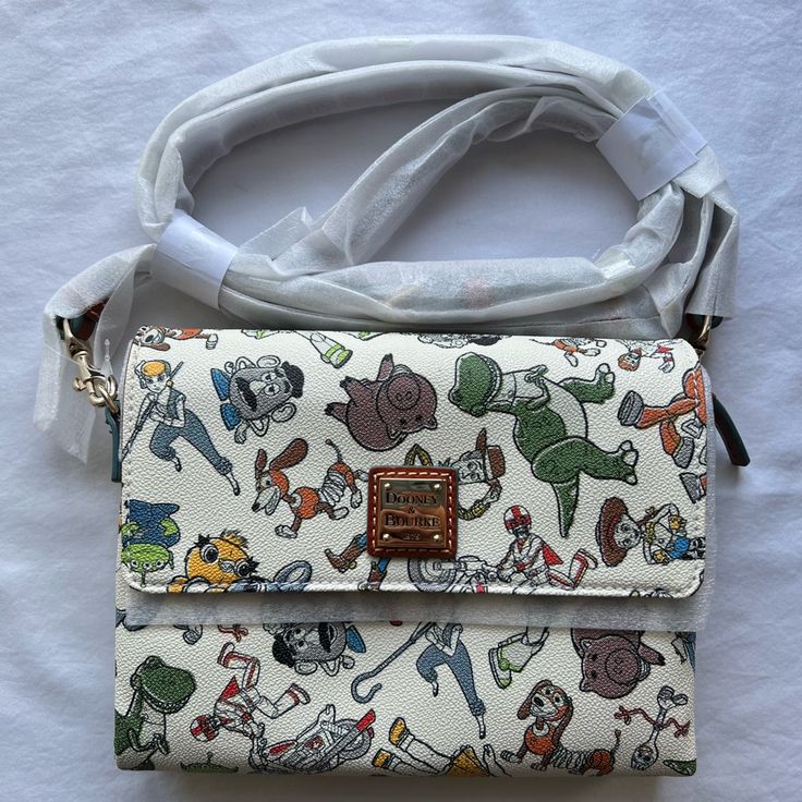 - Dooney & Bourke Toy Story 4 Crossbody Bag - Print Includes Buzz Lightyear, Woody, Jessie, Bullseye, Hamm, Mr And Mrs Potato Head, Rex, Slinky Dog, Bo Peep, Forky, Ducky, Bunny, Duke Caboom, And Gabby Gabby - Screen Set On Coated Cotton - Flap Top With Magnetic Snap Closure - Adjustable And Removable Crossbody Strap - Dimensions: 10” H X 12” W X 4.5” D - Strap Drop Length: 27”L - Brand New With Tags, In Original Packaging With Card And Strap Still Wrapped - Smoke Free Home Feel Free To Make Off Multicolor Character Print Bags For Daily Use, Multicolor Character Print Travel Bag, Themed Multicolor Bags With Character Print, Disney Themed Multicolor Bags For Fan Events, Themed Multicolor Bags For Disney Fan Events, Themed Multicolor Character Print Bags, Disney Crossbody Bags For Disney Trips, Disney Style Crossbody Bags For Disney Trips, Disney Style Crossbody Bag For Daily Use