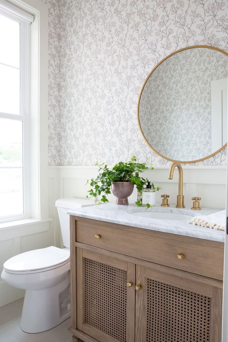 a white toilet sitting next to a bathroom sink under a large mirror above a wooden cabinet