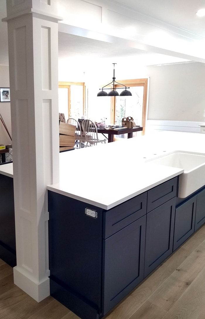 a kitchen with an island in the middle and white counter tops on each side, along with dark blue cabinets