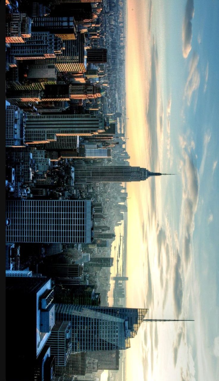 an aerial view of the city skyline with skyscrapers in the foreground and clouds in the background