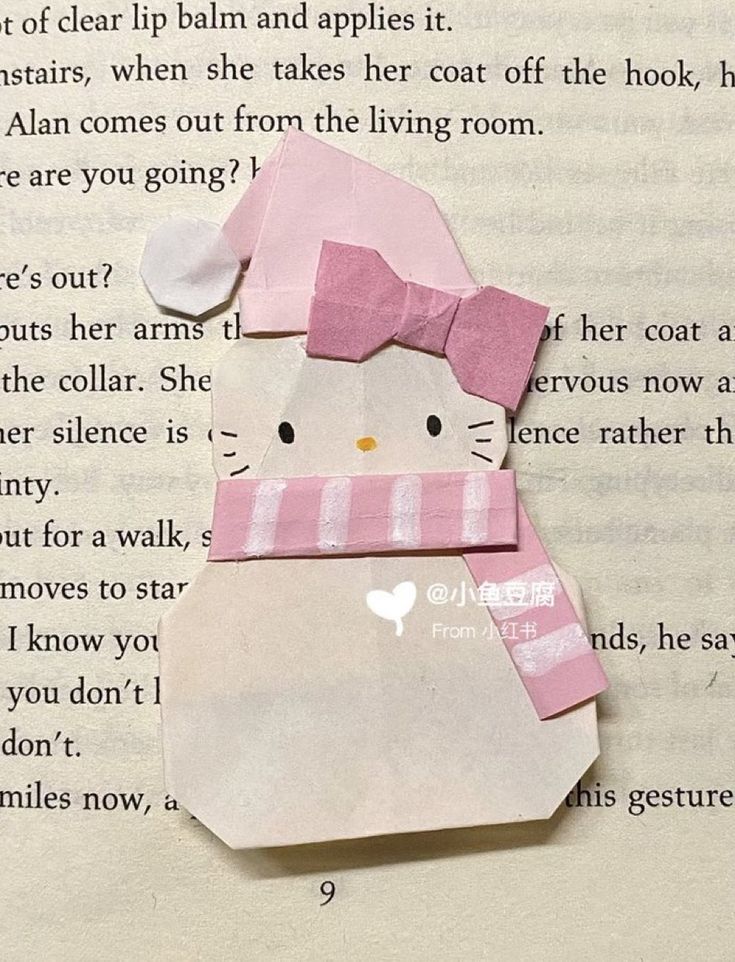 an origami cat with a pink hat and scarf on it's head