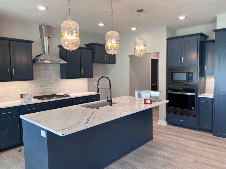 a large kitchen with blue cabinets and marble counter tops, along with an island in the middle