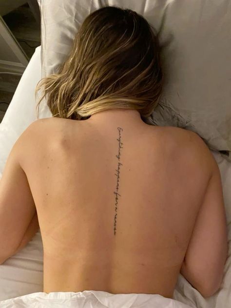 a woman laying in bed with her back turned to the camera and tattoos on her lower back